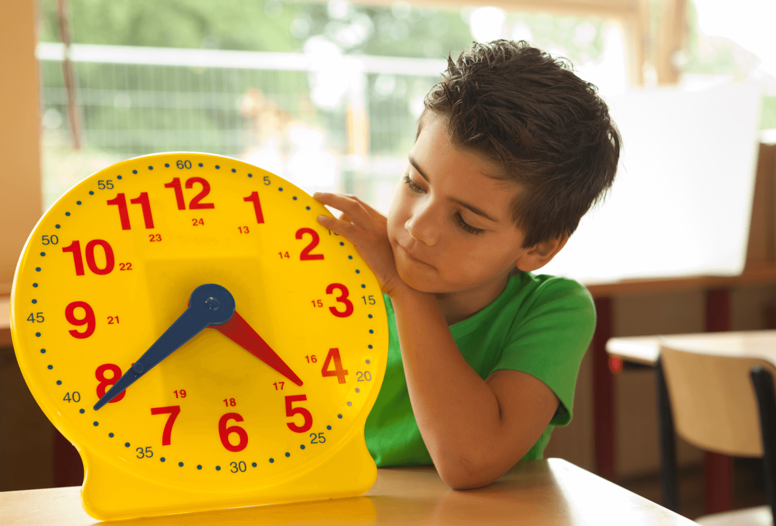 Little boy holding a yellow clock to learn how to tell time with strategies for teaching elapsed time with clocks